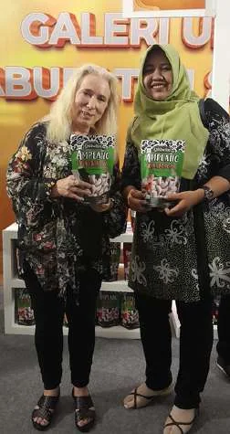 Qisbelin founder with a customer holding Amplang Kuku Macan at a gallery